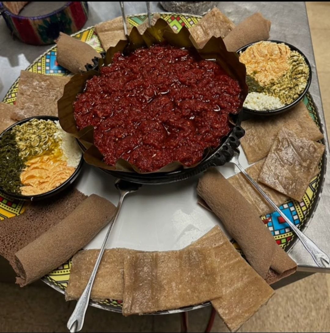 Kitfo platter with injera rolls and traditional sides