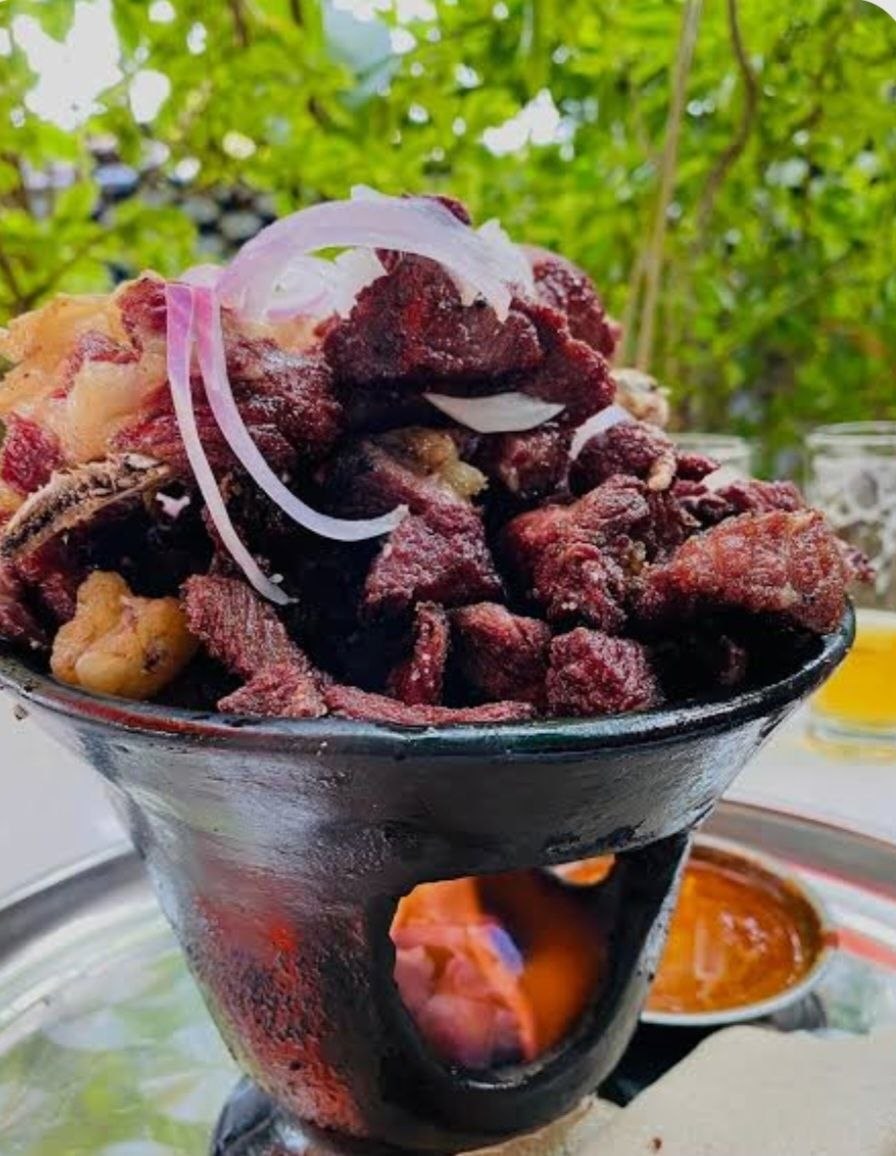 Sizzling tibs piled high in a traditional clay fire pot