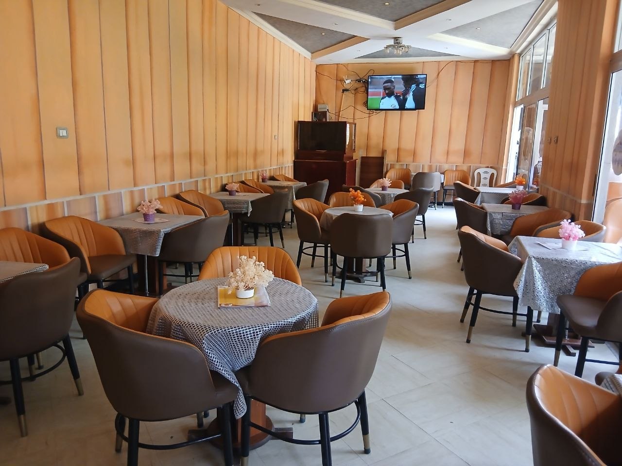 The warm timber-panelled dining room at Hordofa Lodge with leather armchairs and set tables